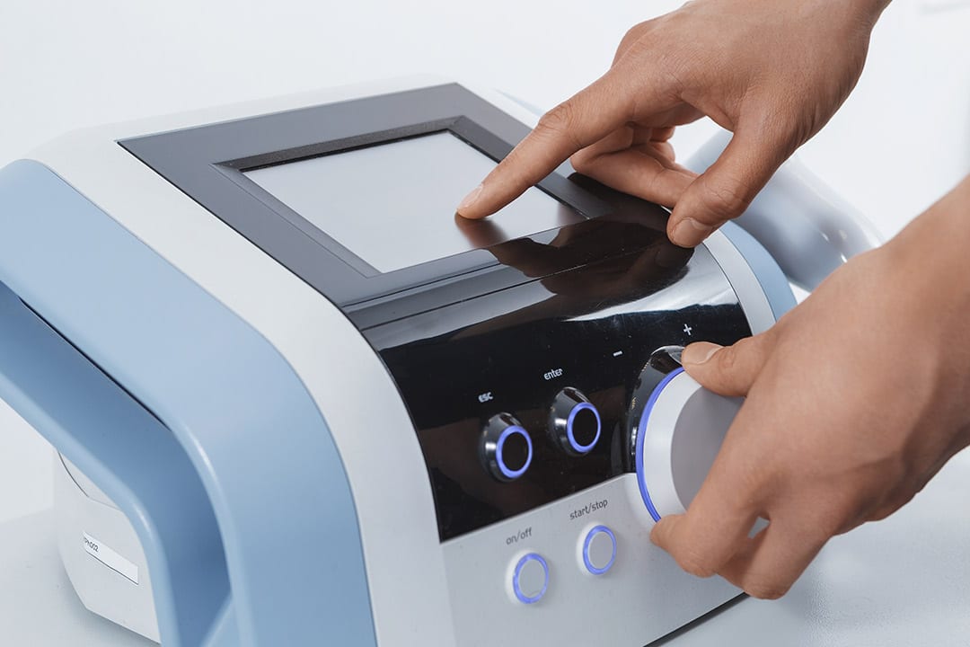 Shockwave therapy machine. A person using a handheld device for skin treatment, highlighting the intersection of technology and personal care.