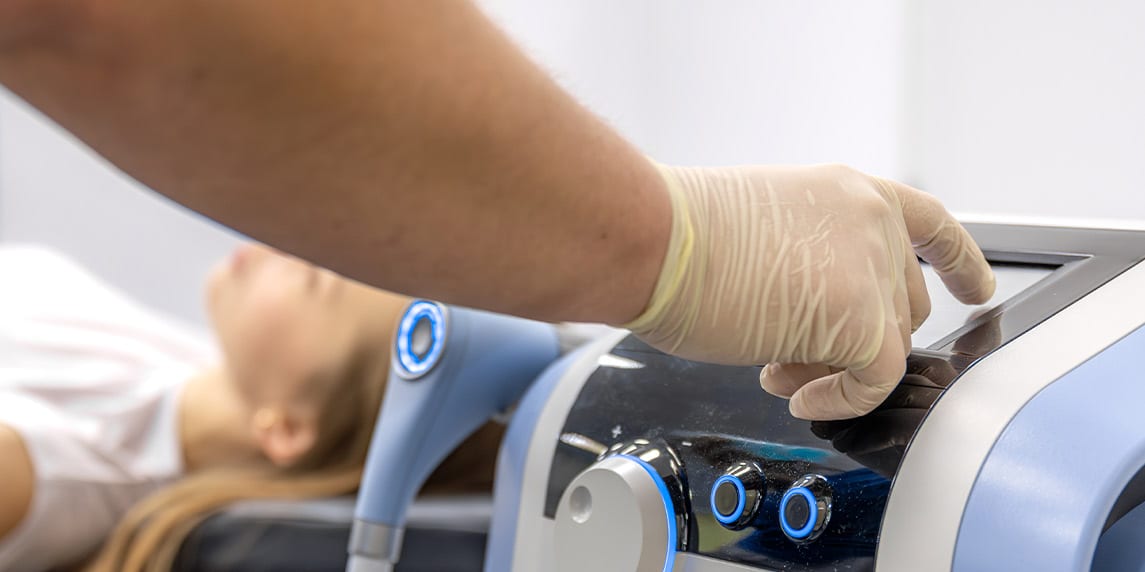 A healthcare professional uses an electronic device to provide treatment to a patient, highlighting modern medical technology.